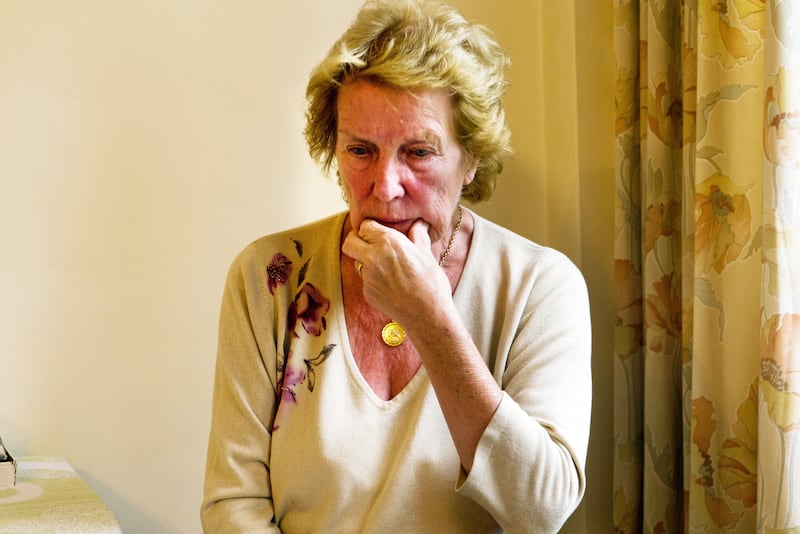 An elderly woman with Alzheimer’s sitting in her home looking confused and worried