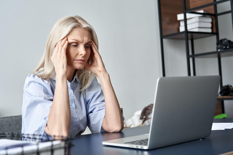 Stressed senior business woman suffering from a headache while sat at her desk in an office