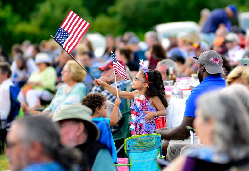 Gabriella Willams, five, waves an American flag during the Symphony of Stars as part of the 2024 Vermont Symphony Orchestra Summer Festival Tour in Grafton, Vermont (Kristopher Radder/The Brattleboro Reformer/AP)