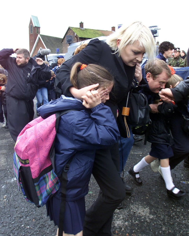 Children and parents run for cover along the Ardoyne Road in north Belfast, towards Holy Cross School