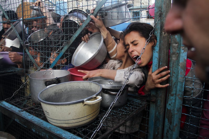 Palestinians line up to receive free meals at Jabaliya refugee camp in the Gaza Strip on March 18 2024 (AP)