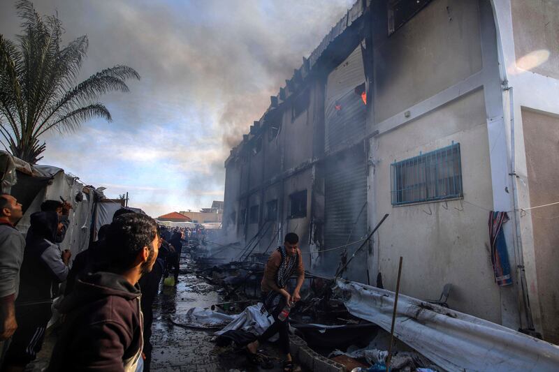 Palestinians try to extinguish a fire at a UNRWA vocational training centre building in Khan Younis which displaced people have been using as a shelter (Ramez Habboub/AP)