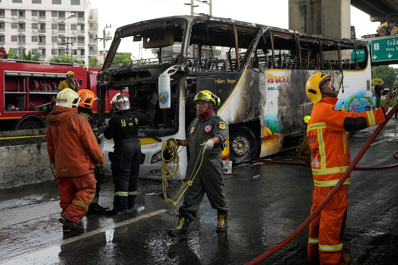 Rescuers work at the site of a bus that caught fire, carrying young students with their teachers, in suburban Bangkok (Sakchai Lalit/AP)