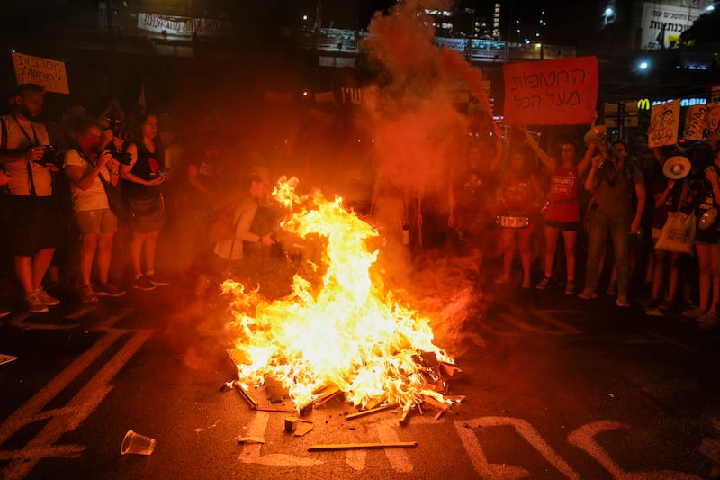 Demonstrators light a bonfire during a protest demanding a ceasefire deal and the immediate release of hostages held by Hamas in the Gaza Strip (AP Photo/Ohad Zwigenberg)