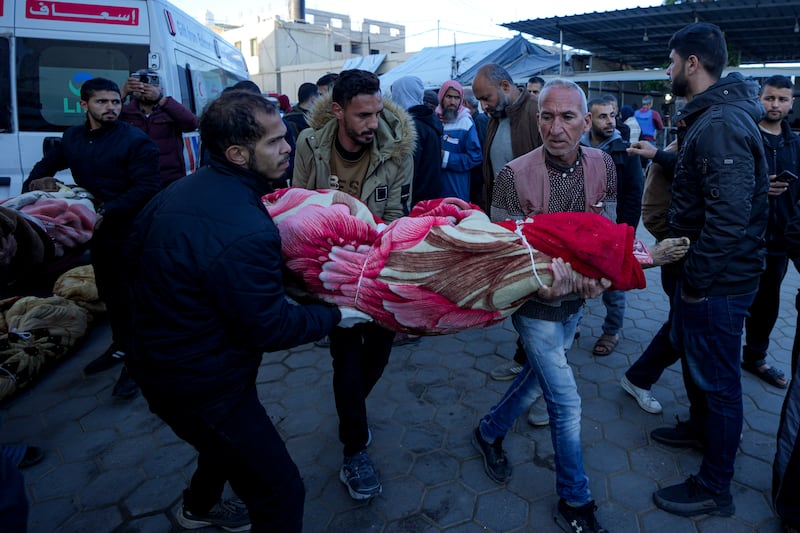 Palestinians carry the body of a relative killed in the Israeli bombardment of the Gaza Strip at a hospital in Deir al-Balah (Abdel Kareem Hana/AP)