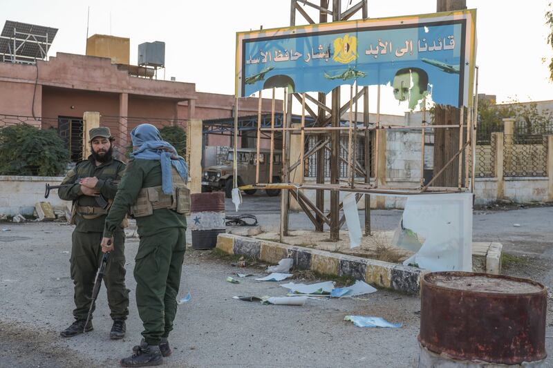 Syrian opposition fighters stand next to a government sign after entering the village of Anjara (Omar Albam/AP)