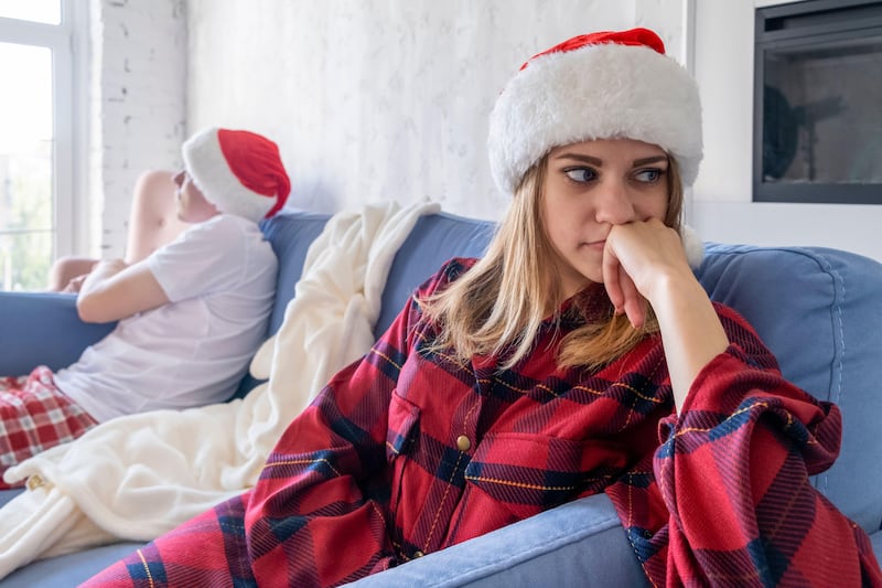 2CTRBC8 Quarrel. Close-up of upset female face. Woman sitting at one end of sofa, while her man siting on other, turning away from her. Family relationships.