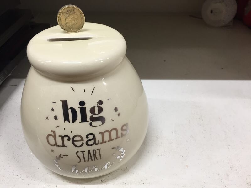 A round pound coin on a money box (PA)