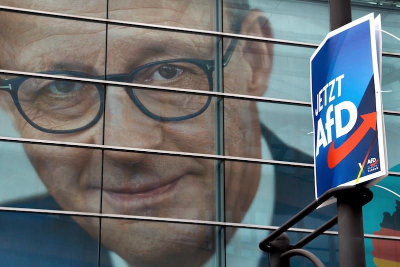 An election poster for AfD in front of a giant election poster showing chairman of the German Christian Democratic Party, Friedrich Merz (Michael Sohn/AP)