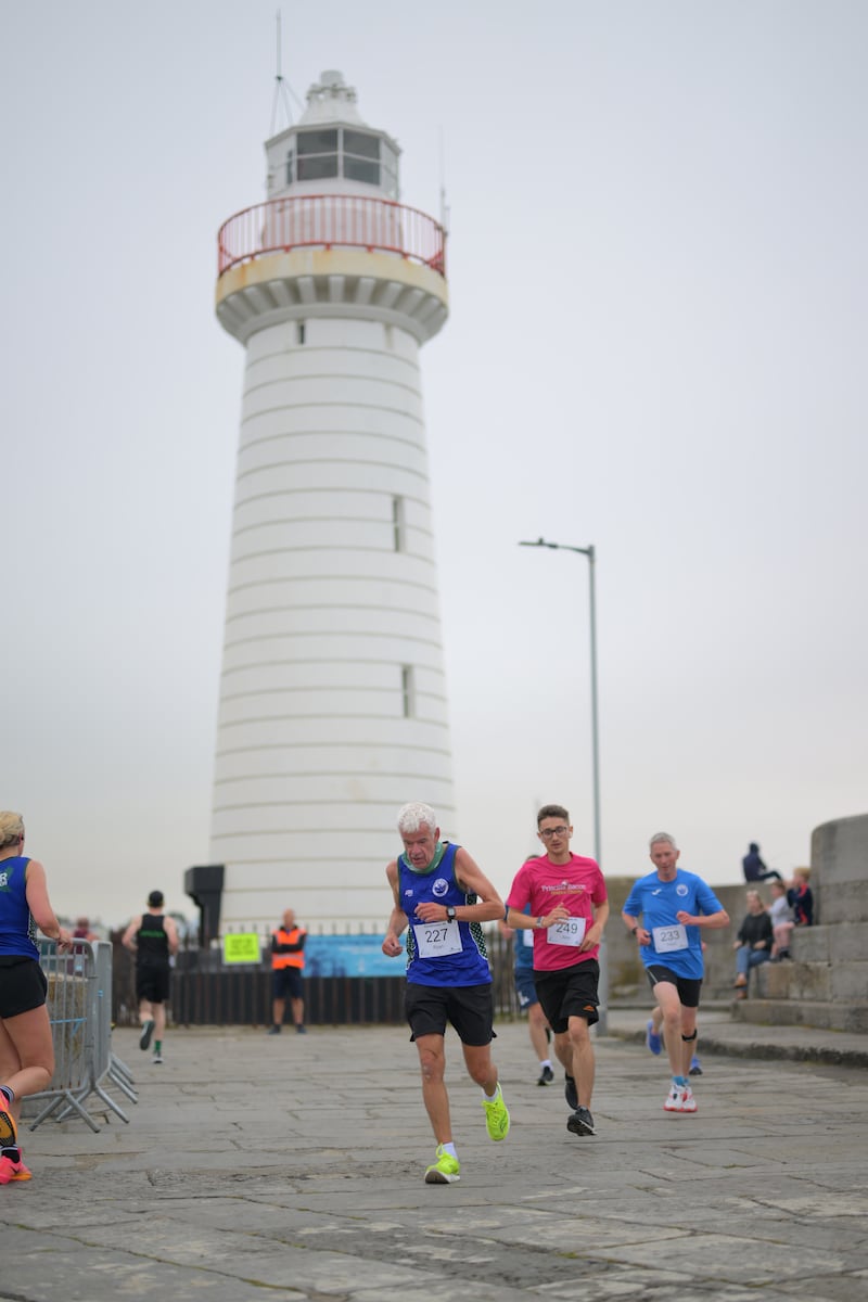 Group of runners in 5k race in front of white lighthouse