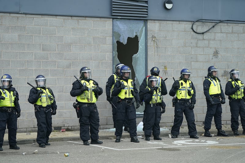 Police officers in front of a smashed window as trouble flared during an anti-immigration protest outside the Holiday Inn Express in Rotherham, South Yorkshire on August 4