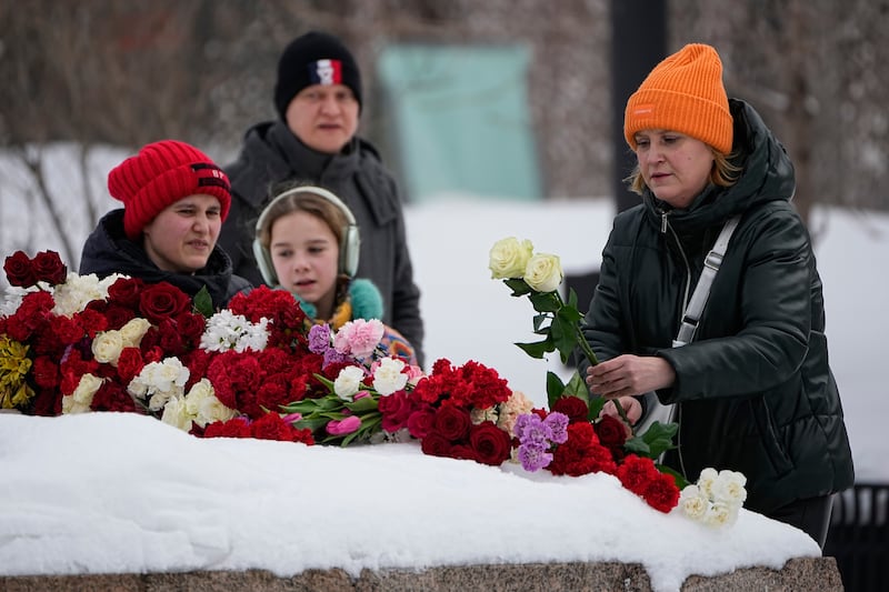 A woman lays flowers to pay last respects to Alexei Navalny at a monument near the Federal Security Service (FSB) building in Moscow (Alexander Zemlianichenko/AP)