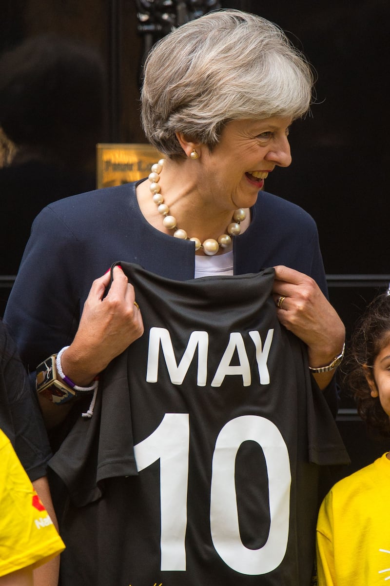 Former prime minister Theresa May is presented with a cricket shirt at a game of street cricket on Downing Street