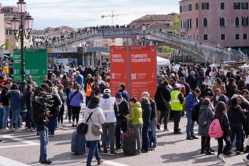 Stewards check tourists’ QR code access outside the main train station in Venice (Luca Bruno/AP)