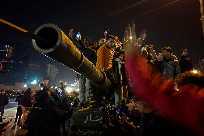 Syrians celebrate the arrival of opposition fighters in Damascus (Omar Sanadiki/AP)