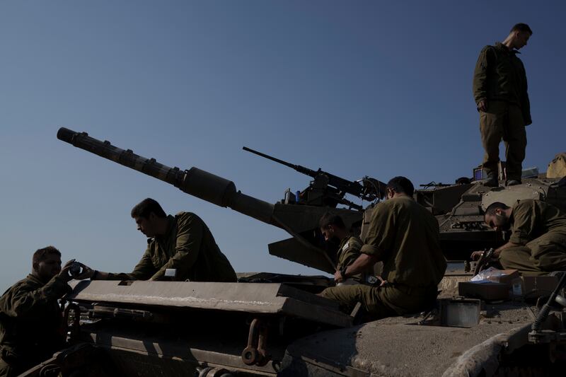 Israeli soldiers work on a tank near the Israeli-Gaza border in southern Israel (Leo Correa/ AP)