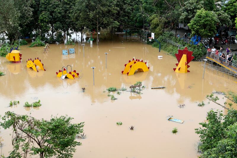 People look at a submerged dragon structure in a playground in Hanoi, following Typhoon Yagi (Huy Han/AP)