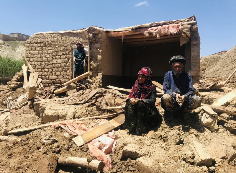 An Afghan couple sit near their damaged home after heavy flooding in Ghor province in western Afghanistan, last month (AP)