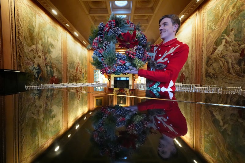 A steward prepares to hang a wreath in the tapestry room as finishing touches are made to Christmas decorations at Dumfries House