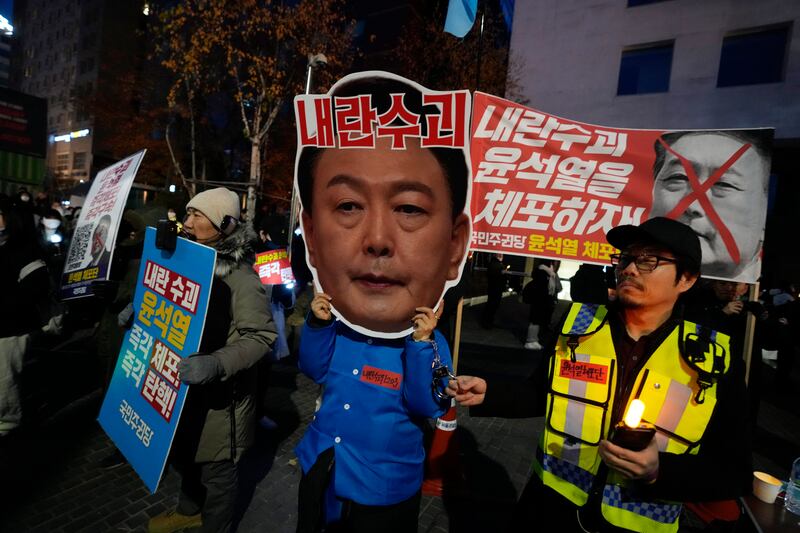 A protester wearing a mask of President Yoon Suk Yeol attends a rally demanding his impeachment outside the National Assembly in Seoul (Ahn Young-joon/AP)