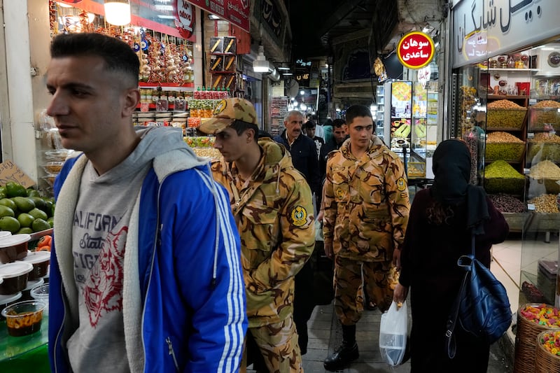 Two army soldiers and people walk through Tajrish traditional bazaar in northern Tehran, Iran, on Saturday (Vahid Salemi/AP)