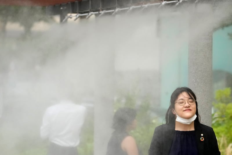 People cool off at a cooling mist spot in Tokyo (Shuji Kajiyama/AP)