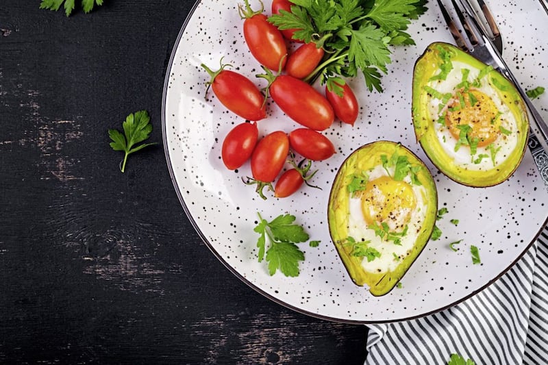 Baked eggs in avocados with tomatoes is a tasty and healthy meal. 