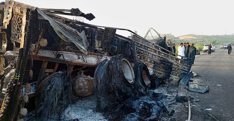 People look at a burnt vehicle which was torched by gunmen after they killed 23 passengers in Musakhail, in south-western Pakistan’s Baluchistan province (Rahmat Khan/AP)