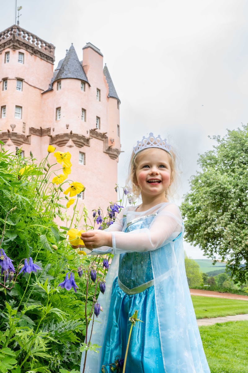 A young girl dressed as a Disney princess playing in the grounds of the newly-renovated Craigievar Castle, Aberdeenshire.