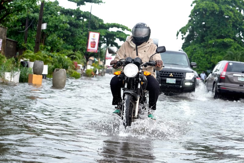 A motorcyclist rides through a flooded street in Lagos, Nigeria (Sunday Alamba/AP)