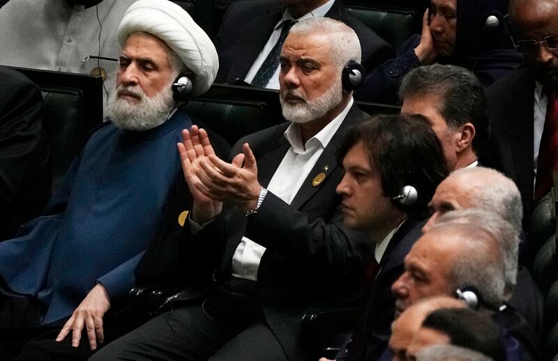 Ismail Haniyeh claps as newly elected Iranian President Masoud Pezeshkian speaks while deputy leader of the Lebanese militant group Hezbollah, Sheikh Naim Kassem, left, sits during the swearing-in ceremony of Mr Pezeshkian in Tehran on Tuesday (Vahid Salemi/AP)