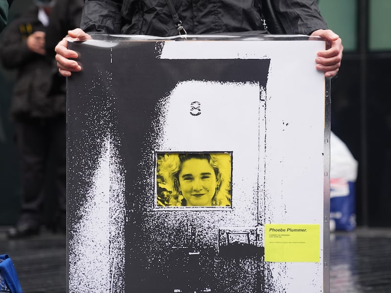 A Just Stop Oil activist holds up a banner of Phoebe Plummer outside Southwark Crown Court