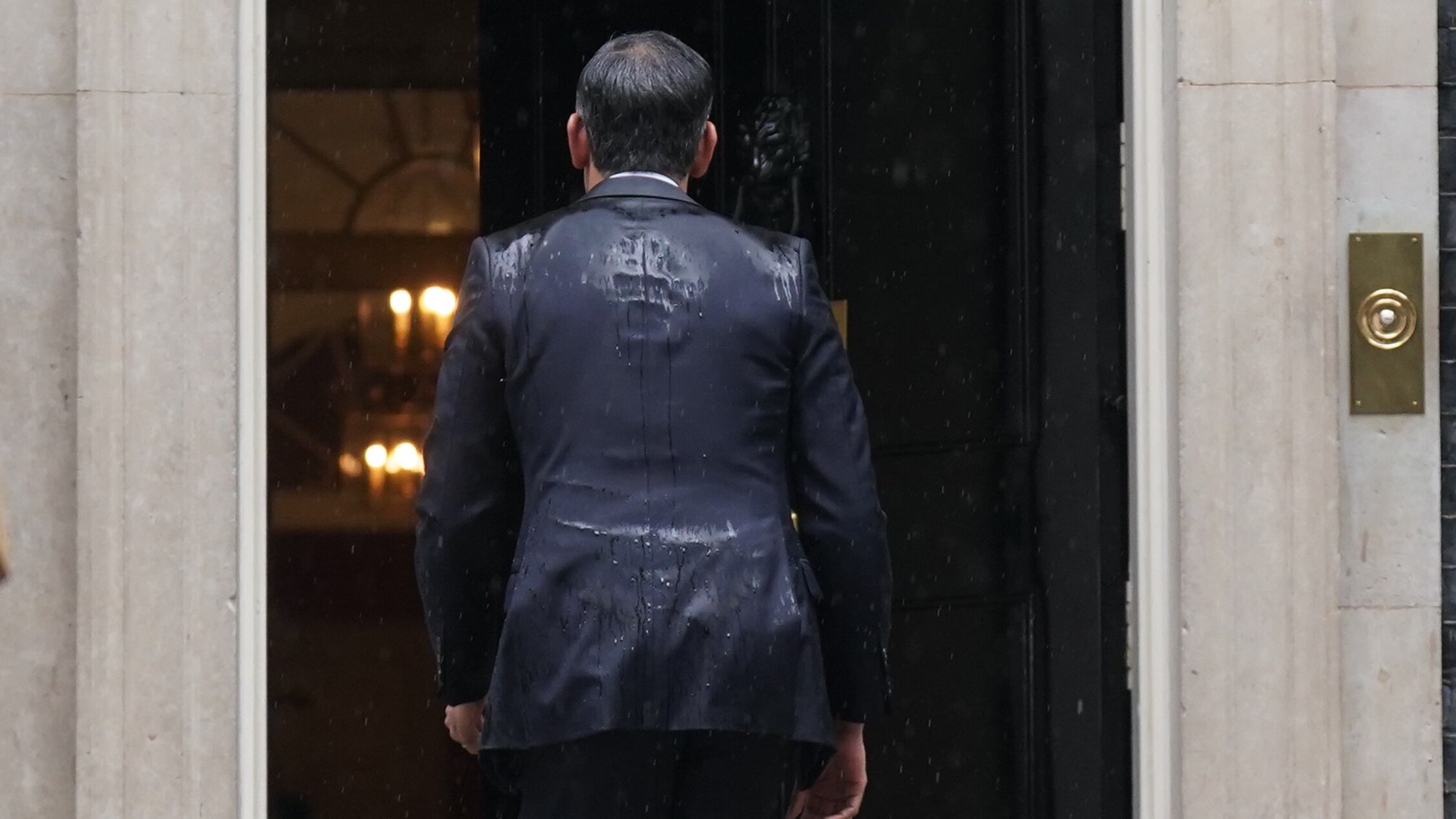 Prime Minister Rishi Sunak, soaked by rain, walks back in to 10 Downing Street