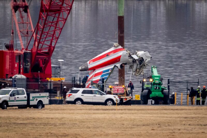 A crane offloads a piece of wreckage onto a flatbed truck near the crash site in the Potomac river (Ben Curtis/AP)