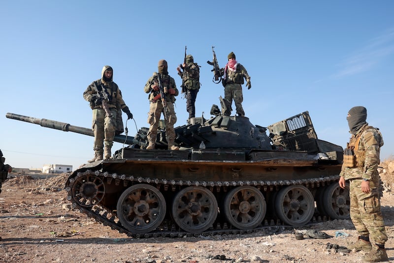 Syrian opposition fighters stand atop a seized military armoured vehicle on the outskirts of Hama, Syria (Ghaith Alsayed/AP)