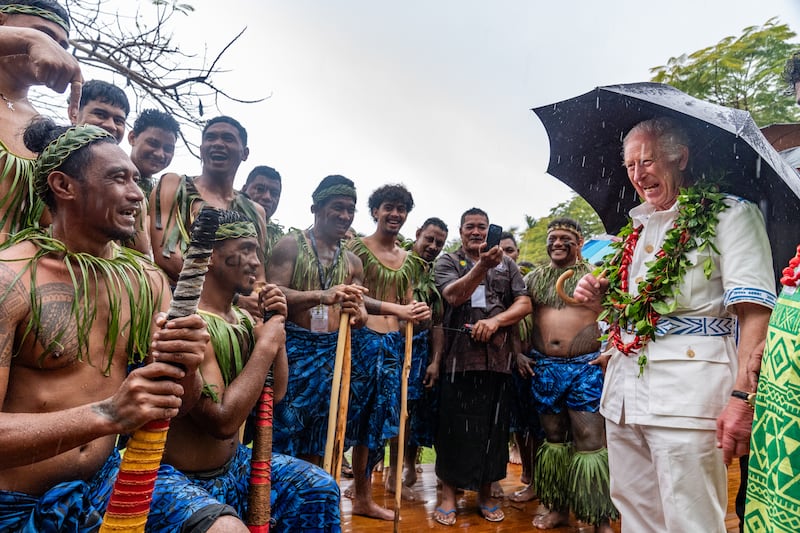 The King shares a joke with members of a cricket team during a visit to the Samoan Cultural Village in Apia