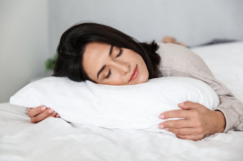 Photo of woman in her 30s with dark hair sleeping in bed