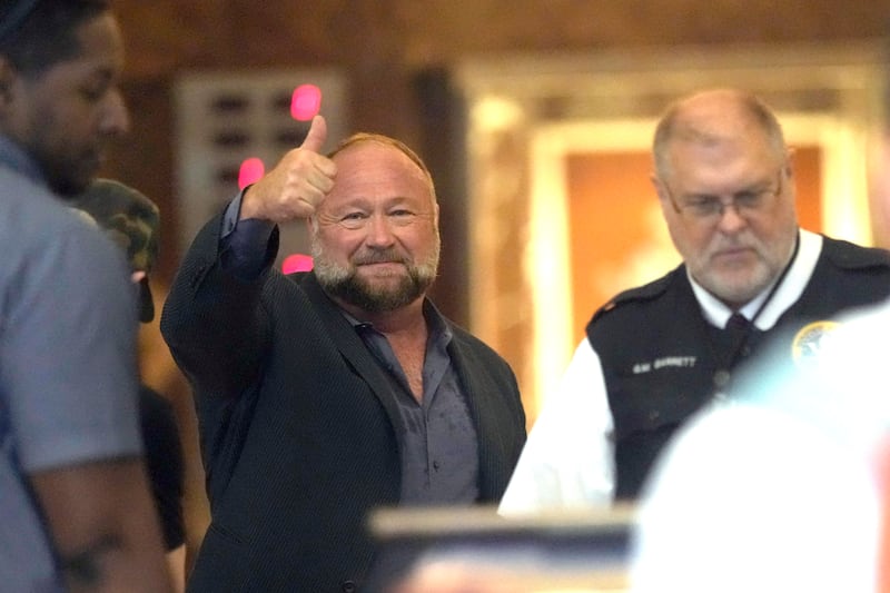 Alex Jones gives a thumbs-up as he goes through security at the Houston court (David J Phillip/AP)