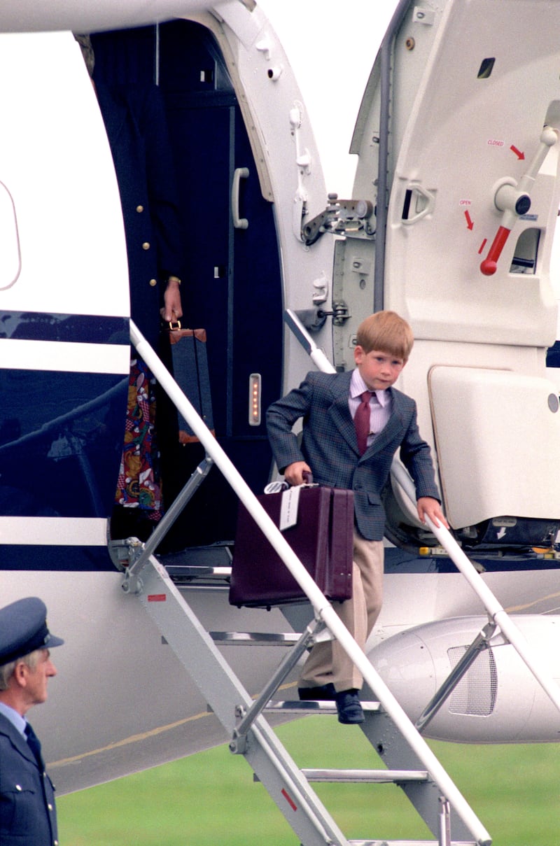 Harry, aged six, carries a briefcase down the down the steps of a plane in Scotland