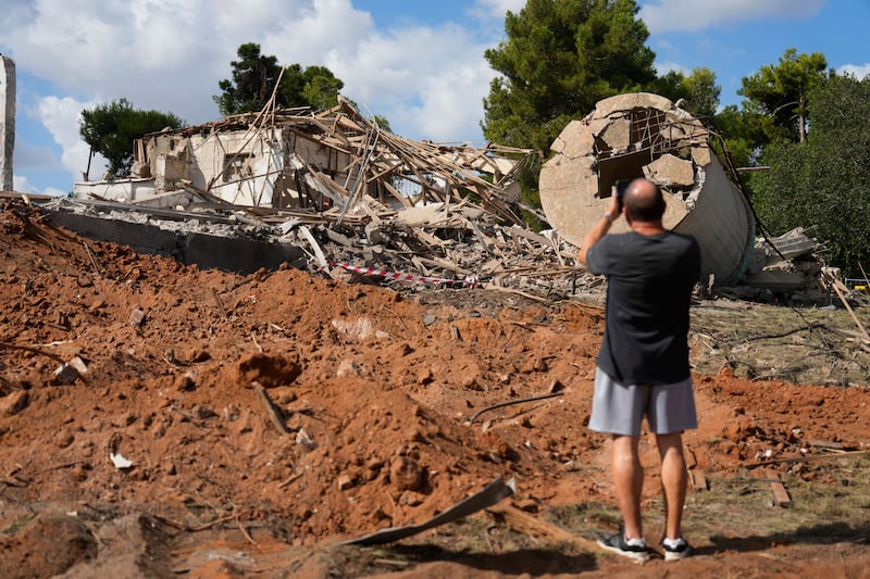 A man takes photos of a destroyed building that was hit in Iran’s missile attack in Hod Hasharon, Israel, early in October (Ariel Schalit/AP)