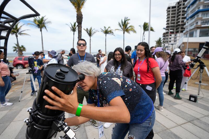 An amateur astronomer prepares her telescope for the total solar eclipse in Mazatlan, Mexico (Fernando Llano/AP)