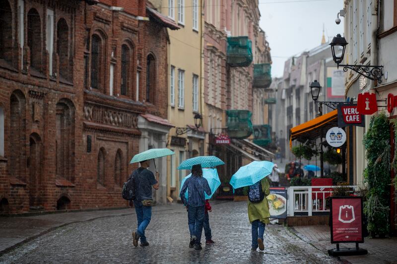 People shelter from the rain under umbrellas in Vilnius, Lithuania (Mindaugas Kulbis/AP)