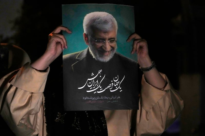 A supporter of Iranian presidential candidate Saeed Jalili holds up a poster of Jalili during his campaign stop in Tehran (Vahid Salemi/AP)