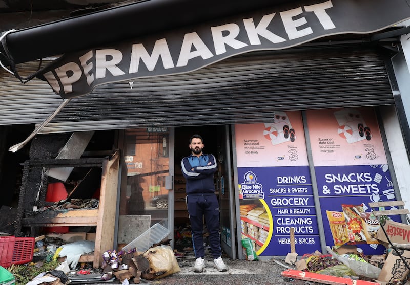 Supermarket owner Abdelkader inspects the damaged after it was set alight for a second time. 
PICTURE COLM LENAGHAN