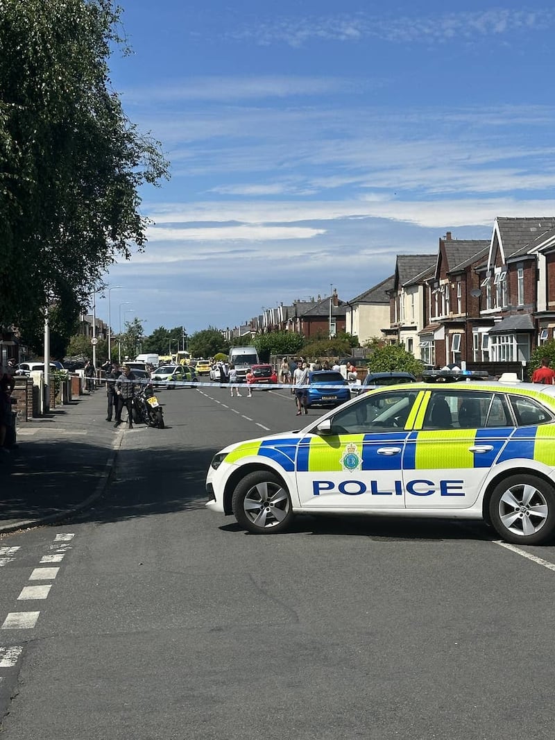 A police car parked in front of police tape on Hart Street in Southport