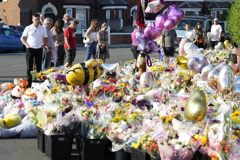 People look at floral tributes on Maple Street, Southport