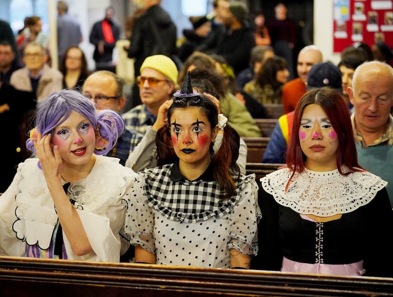 A group wearing elaborate face make-up, with one also sporting a tiny hat on her head