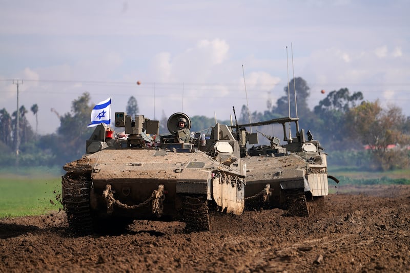 Israeli soldiers drive in armoured vehicles in southern Israel near the border with the Gaza Strip during ongoing ground operations (Tsafrir Abayov/AP)