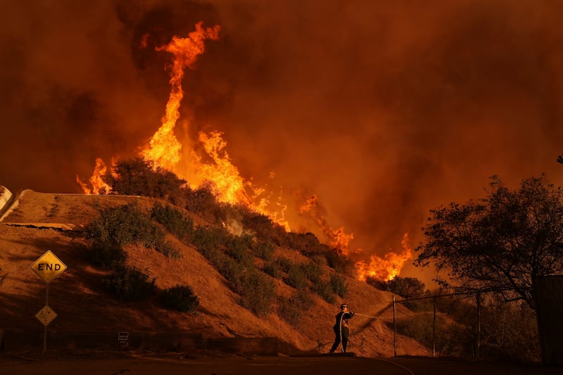 The Palisades Fire burns above a home (Eric Thayers/AP)