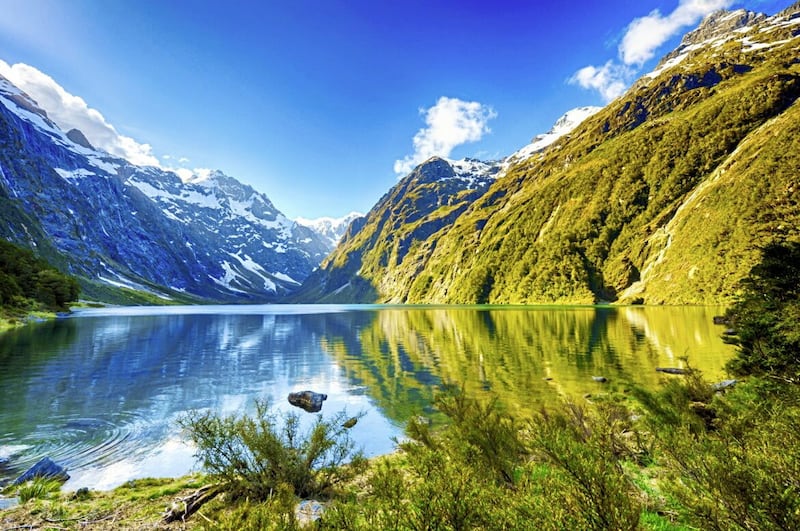 The peaks of the Darran Mountains reflecting in Lake Marian at Fiordland national park in New Zealand&#39;s South Island 